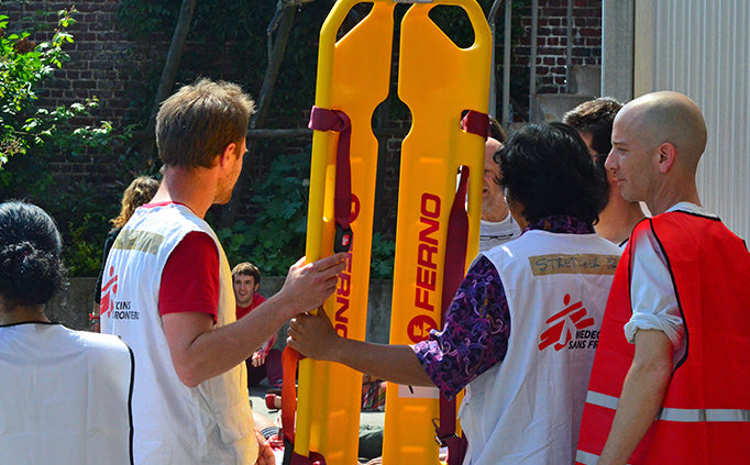 Un groupe d’employés de MSF porte une civière jaune.