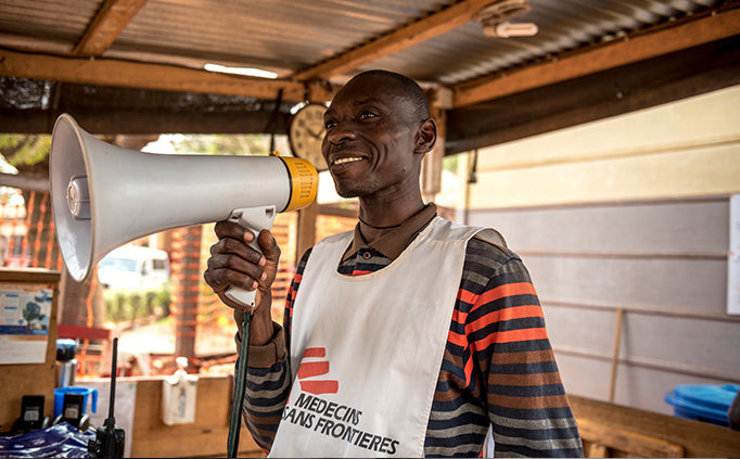 Un employé de MSF tient un mégaphone devant son visage.