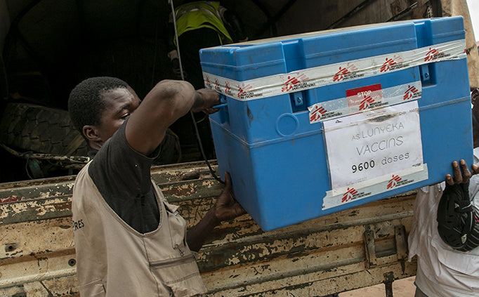 Deux employés de MSF transportent une glacière.