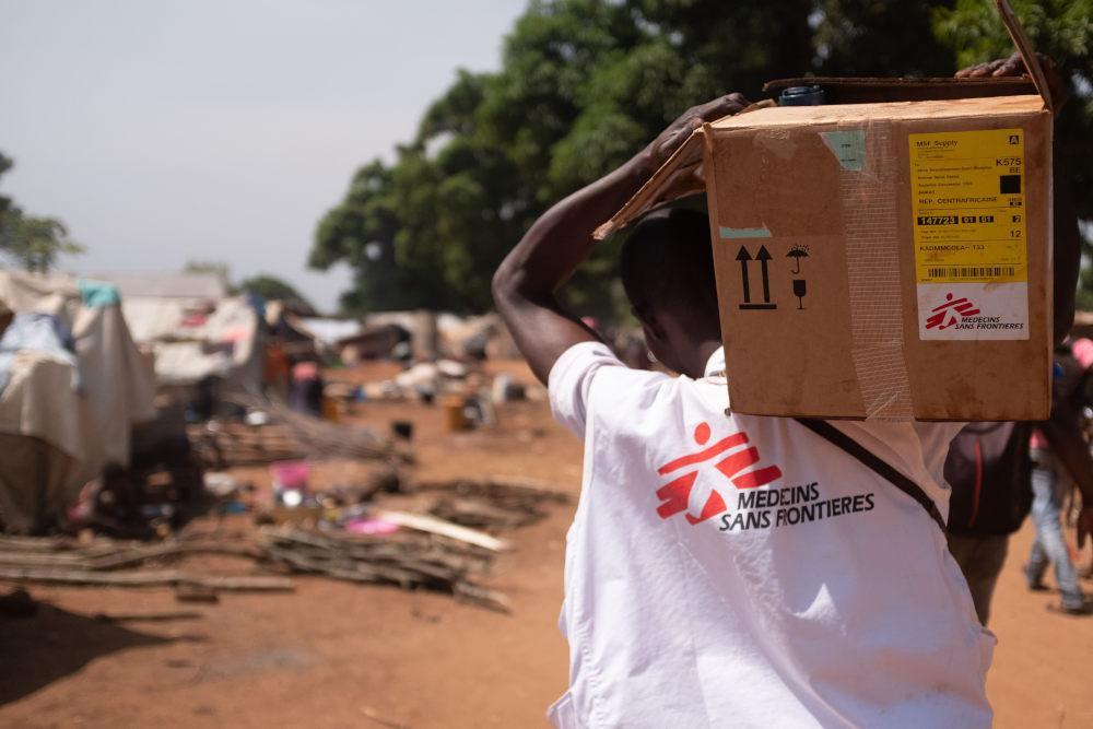 Dans le cadre d’une procédure médicale, une employée de MSF pique le doigt d’un enfant accompagné d’un homme, d’une femme et d’un autre enfant.