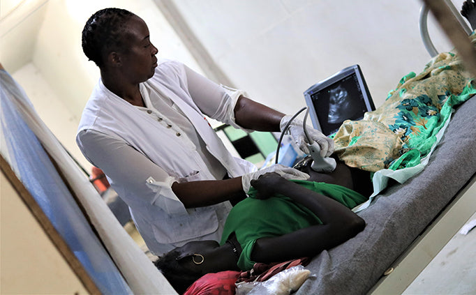 Un agent de santé observe l’écran d’un appareil à ultrasons pendant qu’il examine une patiente.