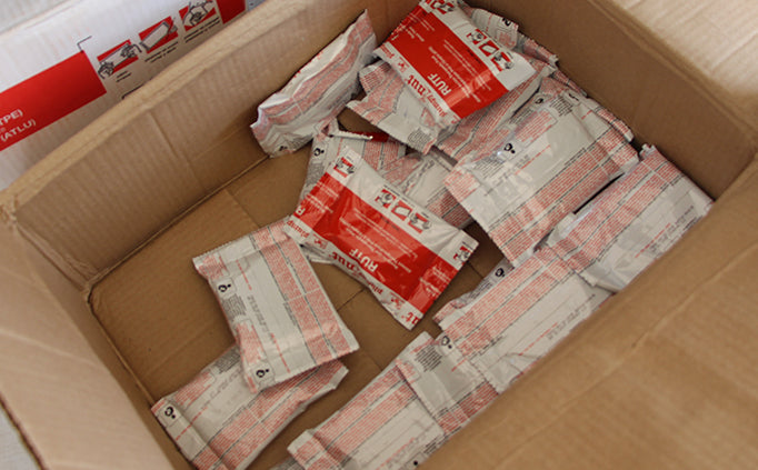 Un carton ouvert contenant des sachets rouges et blancs d’aliments thérapeutiques.