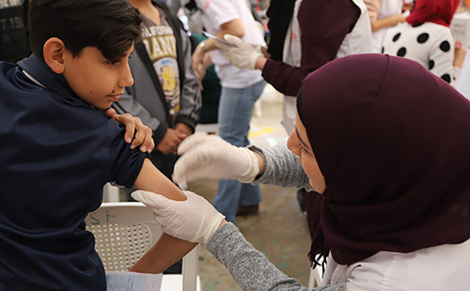 Une infirmière désinfecte le bras d’un enfant avant de lui administrer un vaccin.