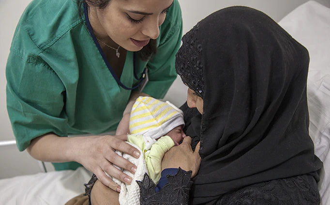 Une agente de santé tend un nouveau-né à sa mère.